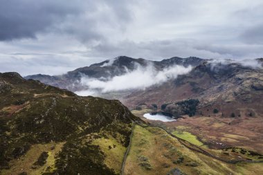 Langdale mızraklarının ve kışın alçak seviye bulutlar ve sisli vadisinin destansı uçan hava aracı görüntüsü.