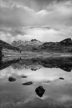 Lake District 'teki Blea Tarn' ın üzerinde kar kaplı Langdale Pikes 'le siyah beyaz güzel kış gündoğumu