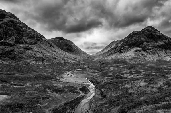 Flying drone dramatic  black and white landscape image of Buachaille Etive Mor and surrounding mountains and valleys in Scottish Highlands on a Winter day