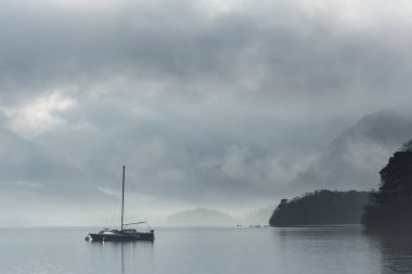 Göl Bölgesi 'ndeki Derwentwater' dan Catbell karlı dağına doğru vadide yoğun bir sis ile süzülen destansı manzara görüntüsü.