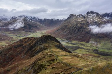 Langdale mızraklarının ve kışın alçak seviye bulutlar ve sisli vadisinin destansı uçan hava aracı görüntüsü.