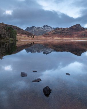 Lake District 'teki Blea Tarn' ın üzerinde kar kaplı Langdale Pikes 'le güzel bir kış gündoğumu.