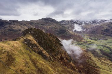 Langdale mızraklarının ve kışın alçak seviye bulutlar ve sisli vadisinin destansı uçan hava aracı görüntüsü.