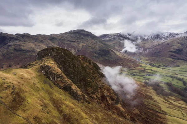 Langdale mızraklarının ve kışın alçak seviye bulutlar ve sisli vadisinin destansı uçan hava aracı görüntüsü.