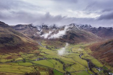 Langdale mızraklarının ve kışın alçak seviye bulutlar ve sisli vadisinin destansı uçan hava aracı görüntüsü.