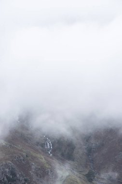 Baş döndürücü kış manzarası. Yan Pike 'tan Langdale mızraklarına doğru. Dağın tepesinde alçak seviye bulutlar ve karamsar sis var.