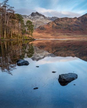 Lake District 'teki Blea Tarn' ın üzerinde kar kaplı Langdale Pikes 'le güzel bir kış gündoğumu.