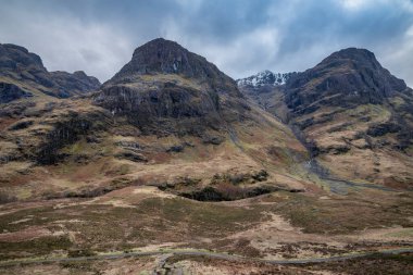 Islak bir kış gününde İskoçya 'nın Glencoe şehrindeki Üç Kız Kardeş' in destansı dramatik manzarası.