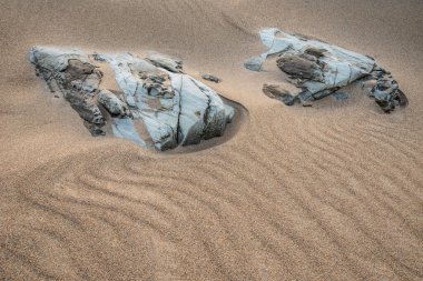 Alışılmadık manzara görüntüsü, büyük kayalıklar ve ovalar gibi sahildeki küçük ölçekli kayaların soyut görünümünü verir.