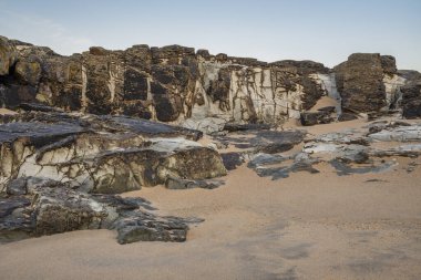 Alışılmadık manzara görüntüsü, büyük kayalıklar ve ovalar gibi sahildeki küçük ölçekli kayaların soyut görünümünü verir.