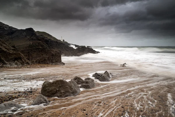 Lighthouse landscape with stormy sky over sea with rocks in fore — Stock Photo, Image