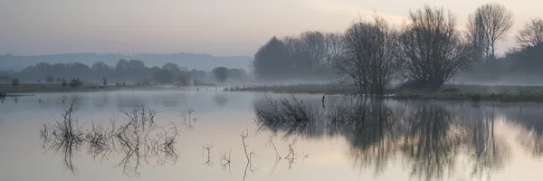 Panorama landschap van lake in mist met zon gloeien bij zonsopgang — Stockfoto