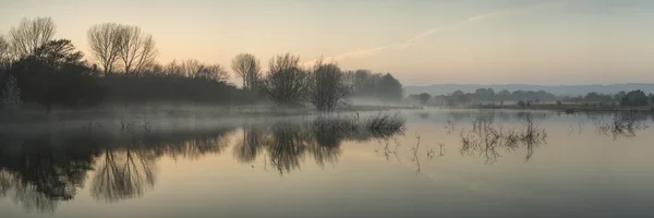 Panorama paisaje de lago en la niebla con el resplandor del sol al amanecer —  Fotos de Stock