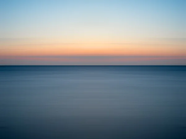 Stunning long exposure seascape image of calm ocean at sunset — Stock Photo, Image
