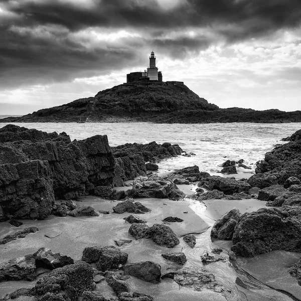 Lighthouse landscape with stormy sky over sea with rocks in fore — Stock Photo, Image