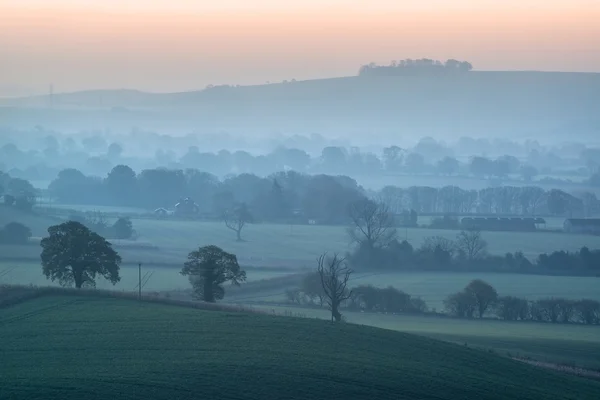 Stunning sunrise over fog layers in countryside landscape — Stock Photo, Image