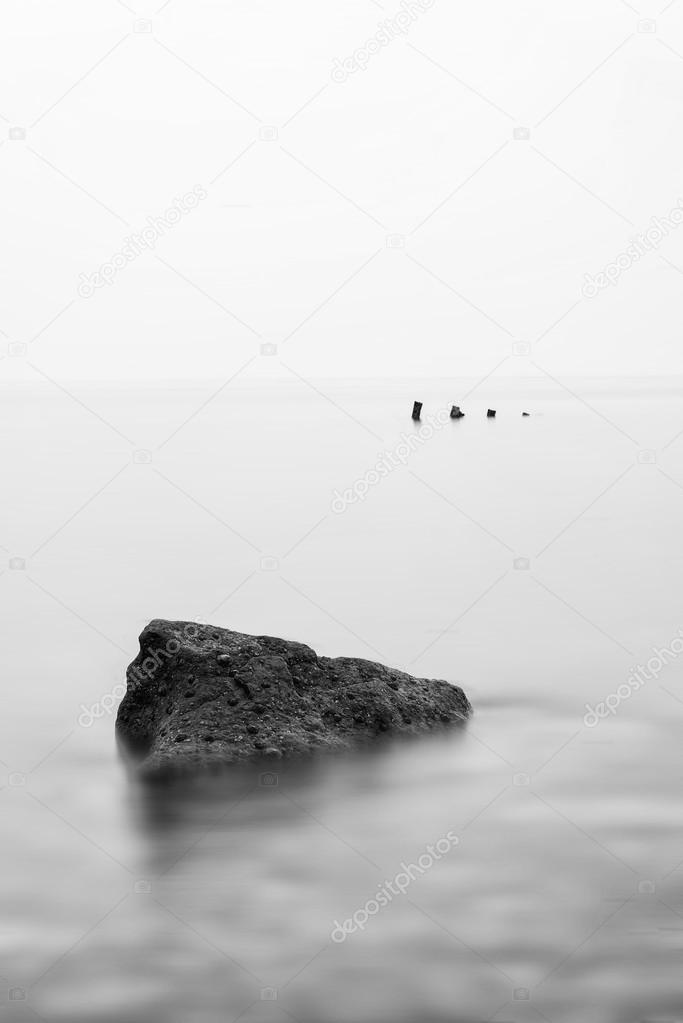 Minimalist landscape image of shipwreck ruin in sea black and wh