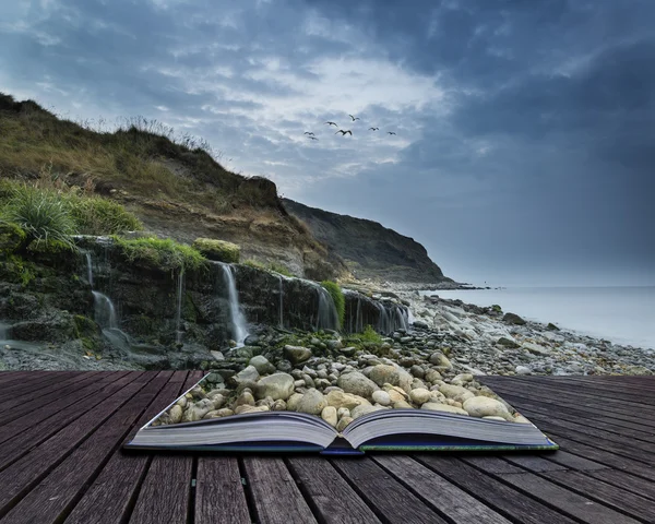 Landscape image of wide waterfall flowing onto rocky beach at su — Stock Photo, Image