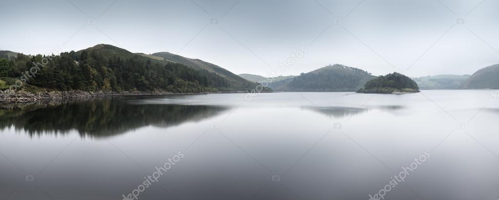 Misty morning landscape panorama over calm lake in Autumn