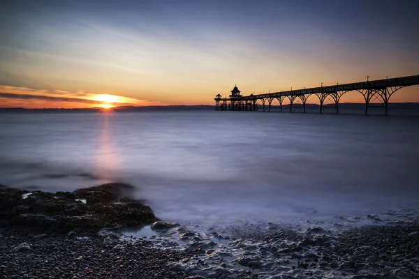 Beautiful long exposure sunset over ocean with pier silhouette — Stock Photo, Image