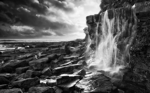 Prachtige landschap afbeelding waterval stroomt in rotsen op strand — Stockfoto