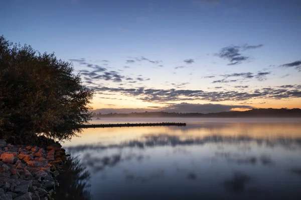 Soluppgång levande landskap av brygga på lugn sjö — Stockfoto
