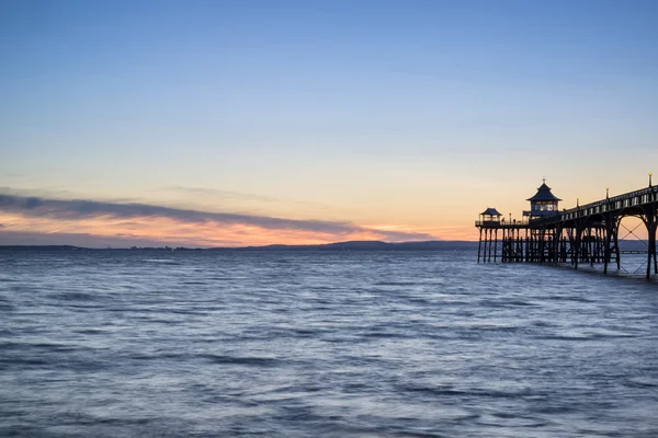 Hermosa larga exposición puesta de sol sobre el océano con silueta de muelle — Foto de Stock