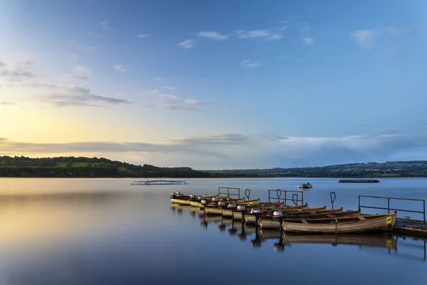 Beautiful landscape sunrise over still lake with boats on jetty — Stock Photo, Image