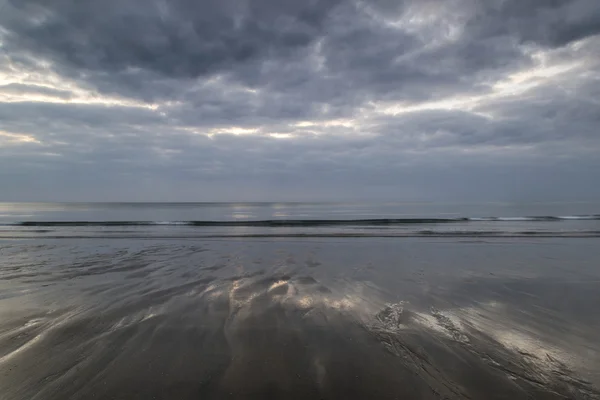 Moody ciel ramatique réfléchi sur le paysage de plage humide — Photo