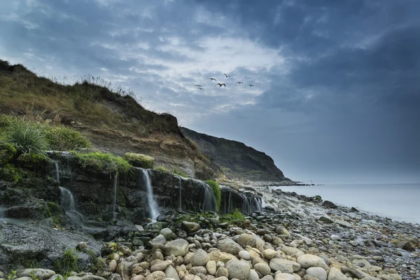 Immagine paesaggistica di ampia cascata che scorre sulla spiaggia rocciosa a su — Foto Stock