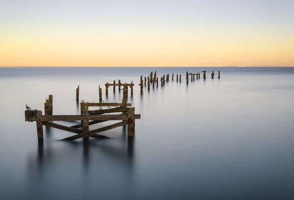 Peaceful concept landscape image of smooth sea and pier ruins — Stock Photo, Image