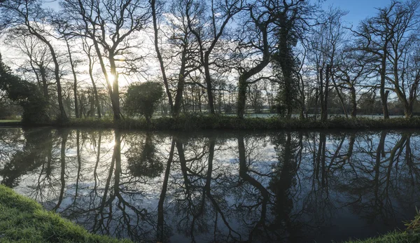 Countryside sunrise landscape with moody sky and flowing river — Stock Photo, Image