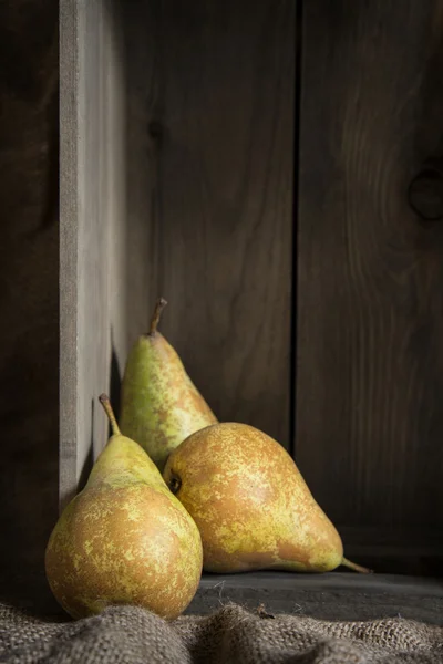 Peras en cocina rústica con caja de madera y saco hessiano — Foto de Stock