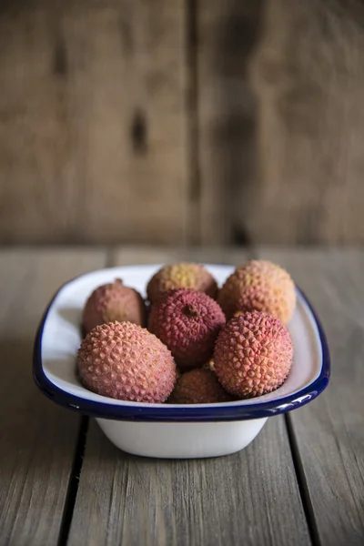 Lychees in rustic setting with wooden background — Stock Photo, Image