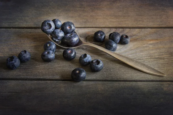 Blueberries in rustic kitchen setting with old wooden background — Stock Photo, Image