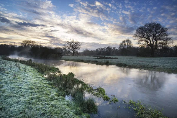 Countryside sunrise landscape with moody sky and flowing river — Stock Photo, Image