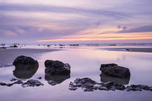 Amanecer paisaje del amanecer en la playa de arena rocosa con cielo vibrante y —  Fotos de Stock