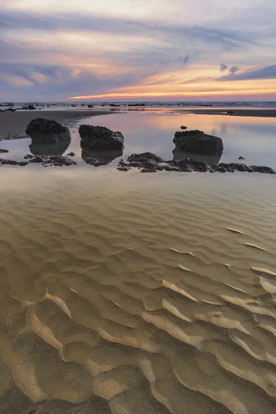 Amanecer paisaje del amanecer en la playa de arena rocosa con cielo vibrante y — Foto de Stock