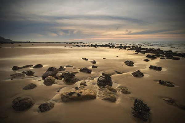 Alba paesaggio alba sulla spiaggia di sabbia rocciosa con cielo vibrante e — Foto Stock