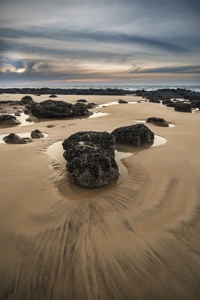 Amanecer paisaje del amanecer en la playa de arena rocosa con cielo vibrante y — Foto de Stock