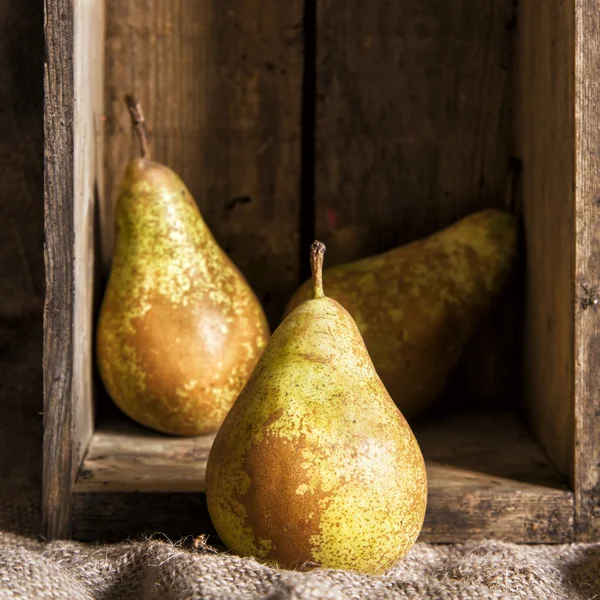 Poires dans un cadre rustique de cuisine avec boîte en bois et sac de Hesse — Photo