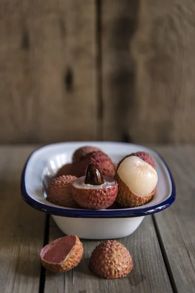 Lychees in rustic setting with wooden background — Stock Photo, Image