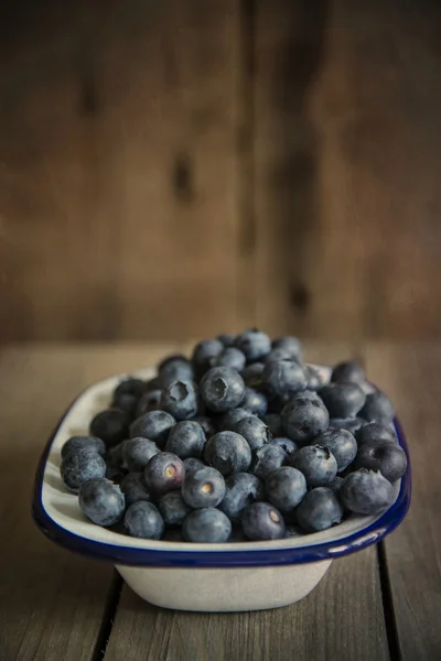 Blueberries in rustic kitchen setting with old wooden background — Stock Photo, Image