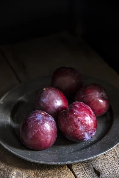 Fresh plums in natural light setting with moody vintage retro st — Stock Photo, Image