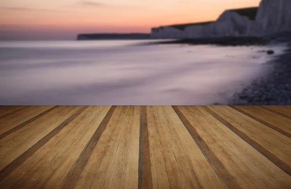 Long exposure landscape rocky shoreline at sunset with wooden pl — Stock Photo, Image