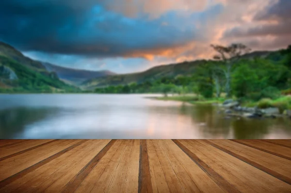 Beautiful sunrise over lake and mountains with wooden planks flo — Stock Photo, Image