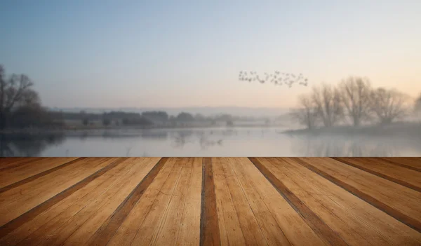 Paesaggio del lago nella nebbia con bagliore di sole all'alba con p di legno — Foto Stock