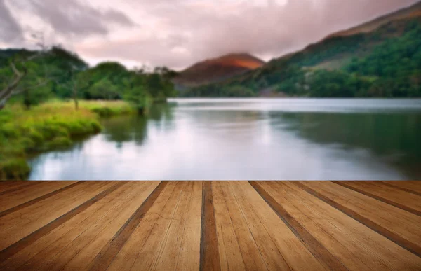 Beautiful sunrise over lake and mountains with wooden planks flo — Stock Photo, Image