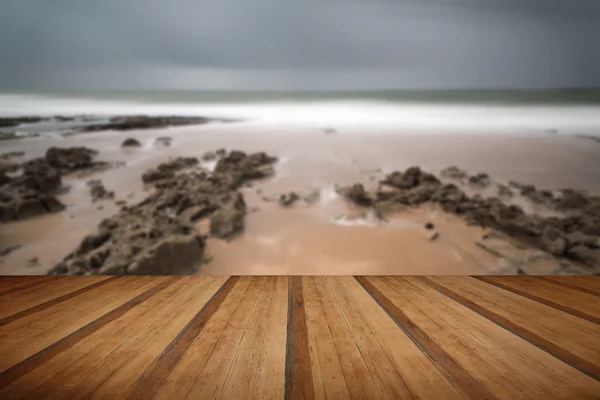 Long exposure landscape beach scene with moody sky with wooden p