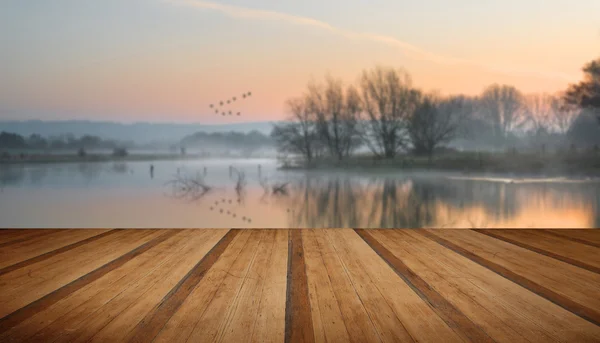 Paesaggio del lago nella nebbia con bagliore di sole all'alba con p di legno — Foto Stock